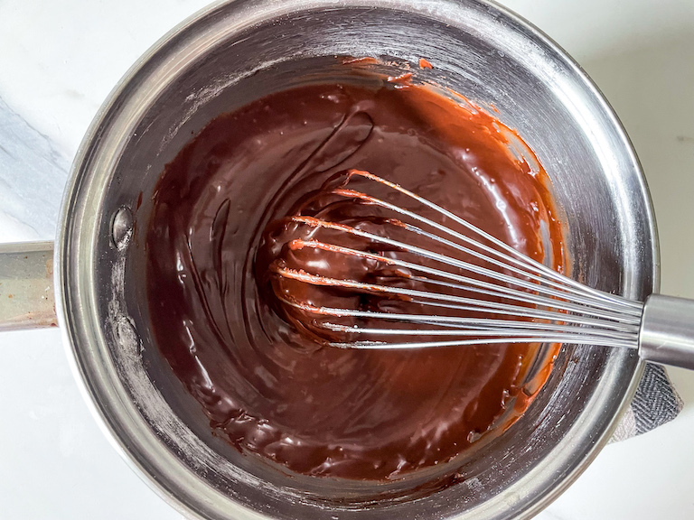 Chocolate frosting and a whisk in a saucepan