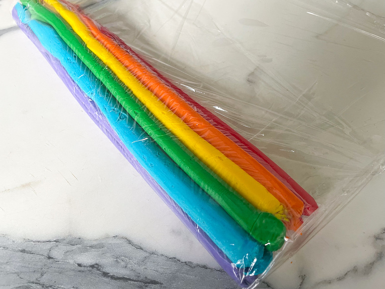 A tube of clingfilm with rainbow buttercream
