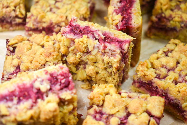 Raspberry oat bars arranged on a sheet of baking parchment