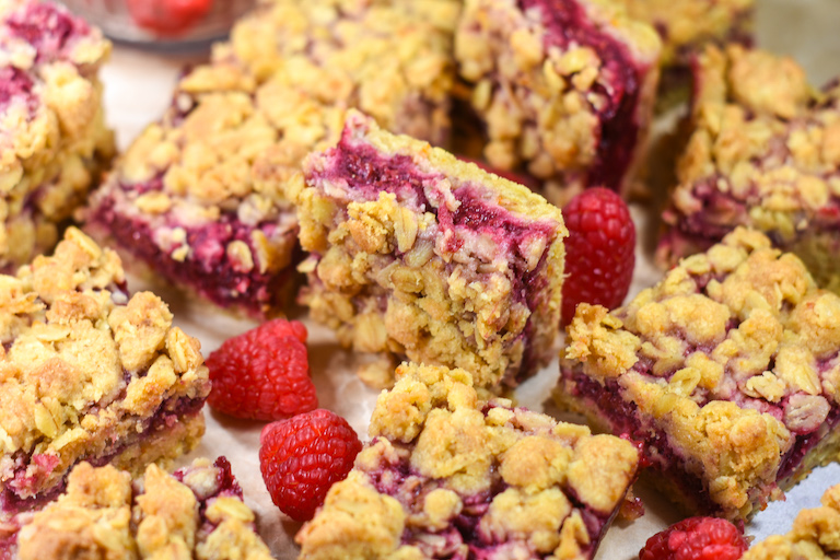 Raspberry bars and fresh berries on parchment
