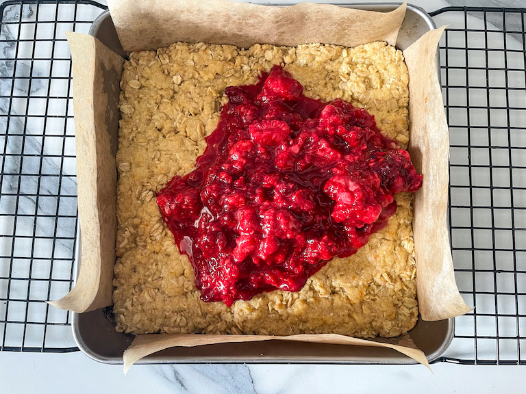 Raspberry topping on base layer in a tin