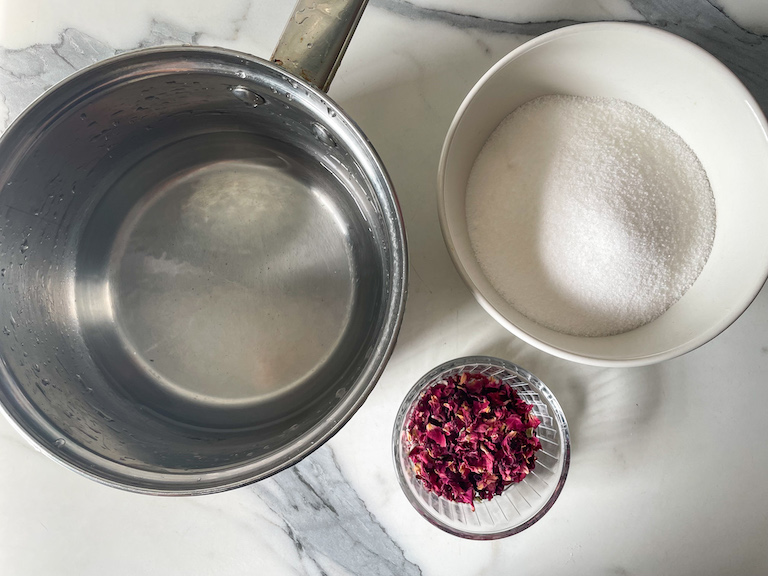 A saucepan, dish of sugar, and dish of dried rose petals