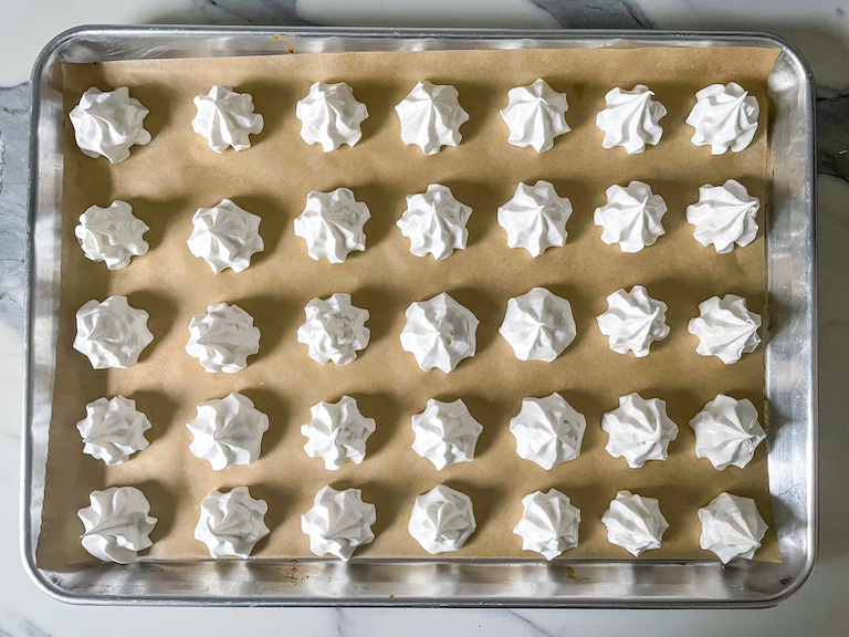 Piped meringue kisses on a tray