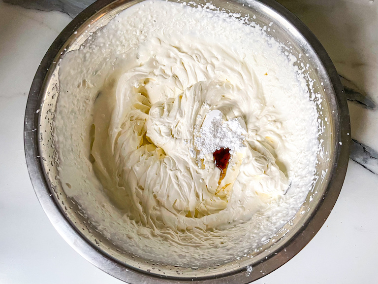 Whipped cream in a bowl with sugar and vanilla
