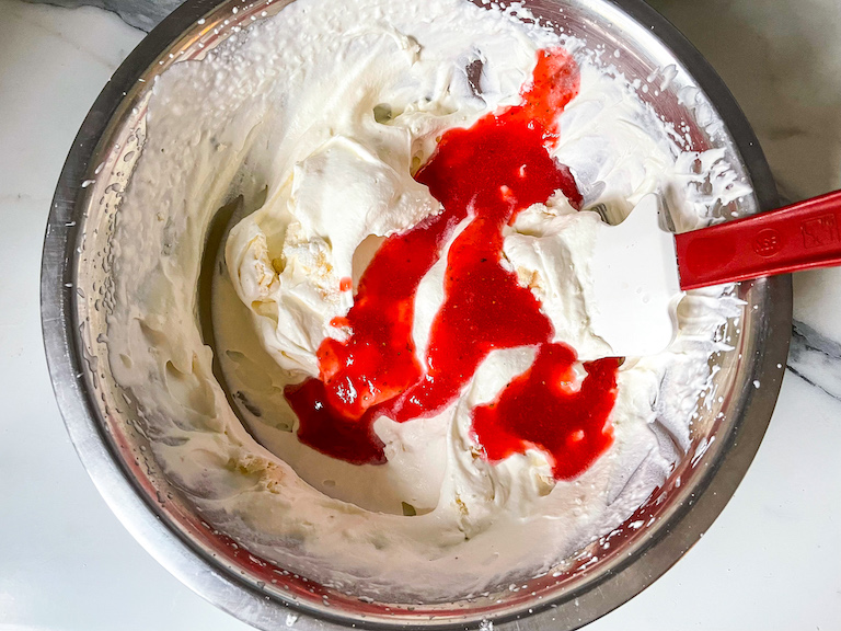 Strawberry sauce in a bowl of whipped cream