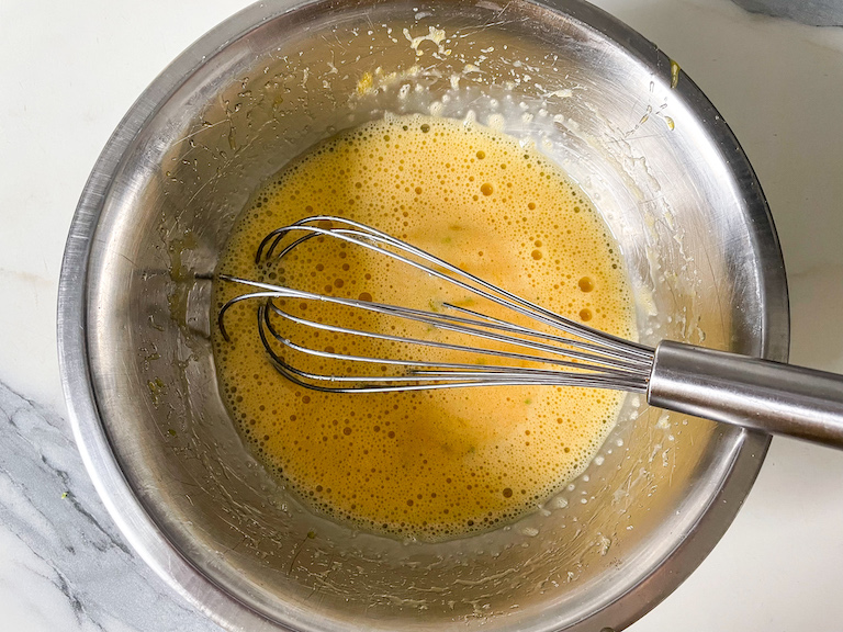 Egg mixture in a bowl with a whisk