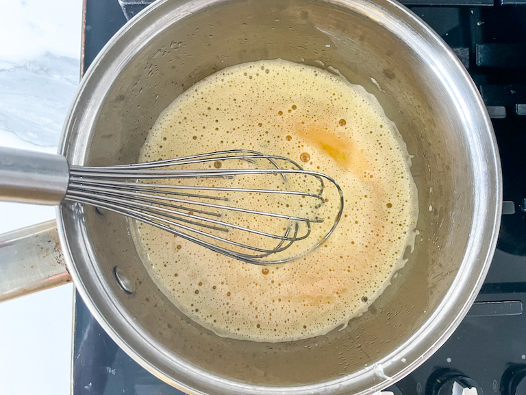 Saucepan with lime curd ingredients and a whisk