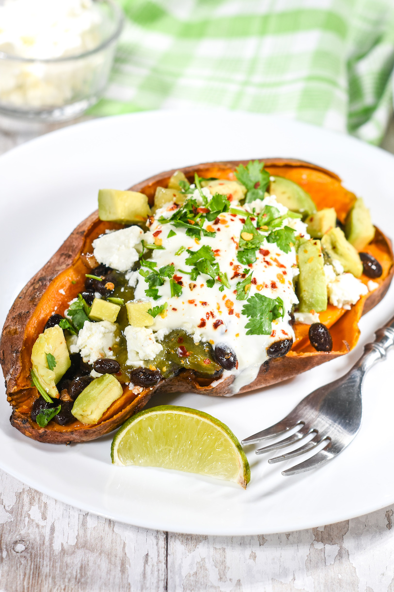 Vegetarian taco sweet potato on a white plate with fork and lime wedge