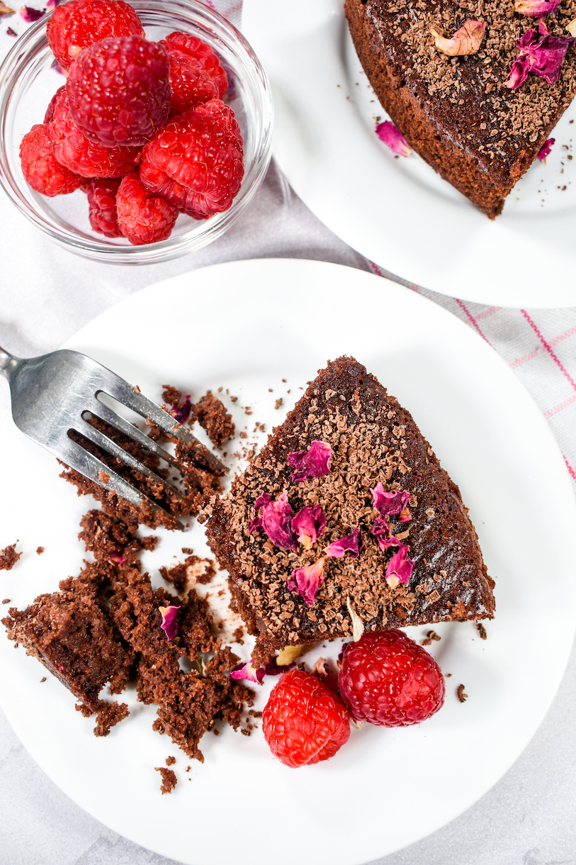 Half eaten slice of chocolate almond cake with raspberries