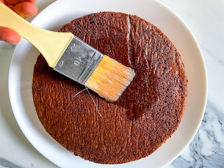 Brushing chocolate cake with rose syrup