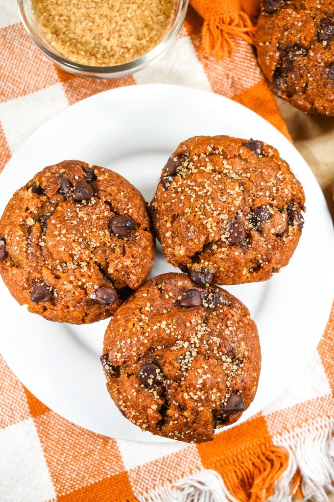 looking down at three chocolate chip pumpkin muffins sprinkled with demerara sugar