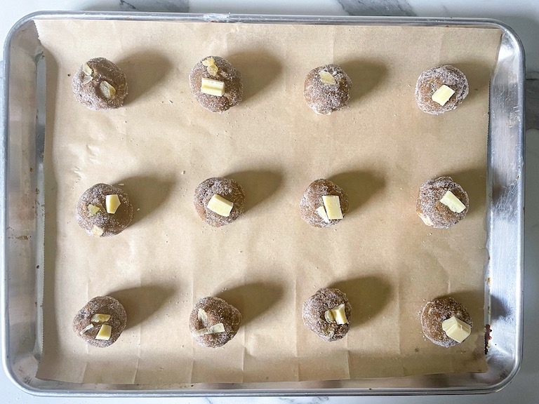 Chunks of white chocolate pressed into balls of unbaked cookie dough