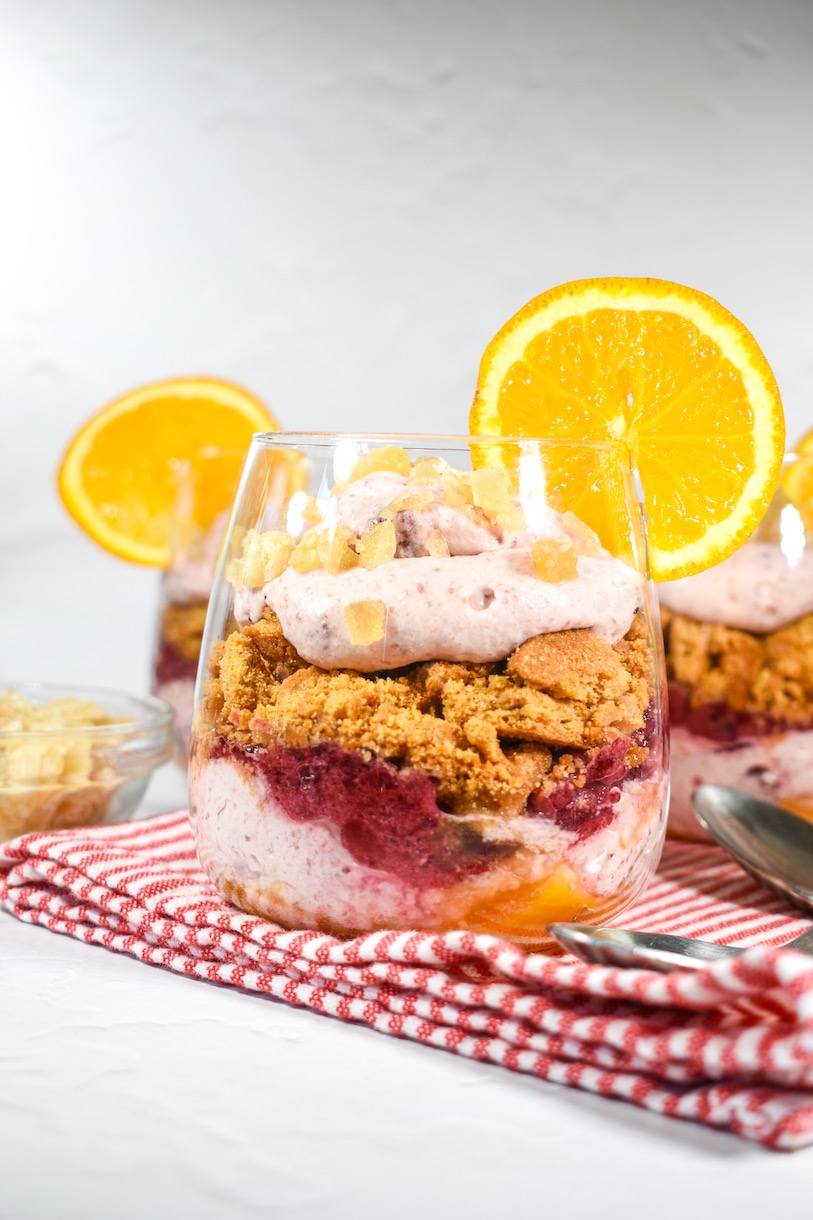 Cranberry and orange parfait in a clear wine glass, garnished with a slice of fresh orange