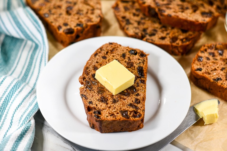 A slice of Welsh tea bread on a plate with a pat of butter on top