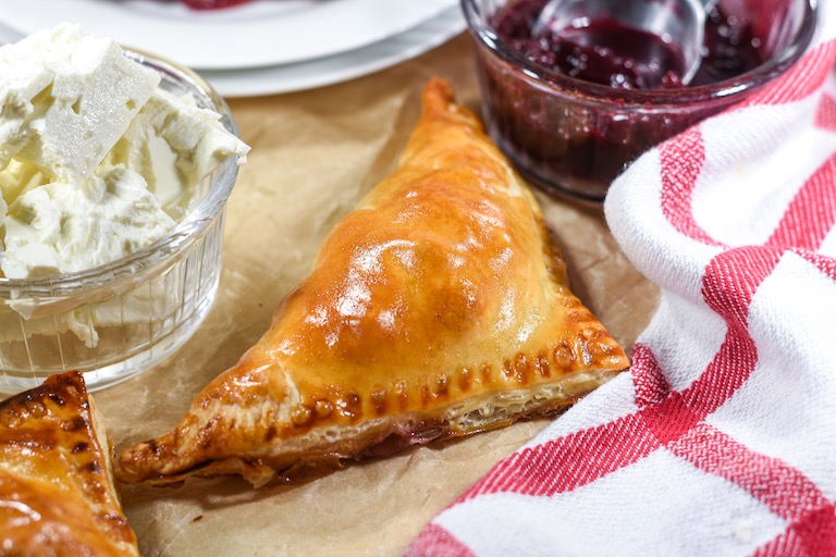 A puff pastry triangle with dishes of cheese and cherry compote