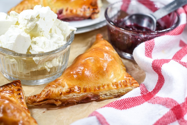 Puff pastry triangle with a dish of feta cheese and dish of cherry compote