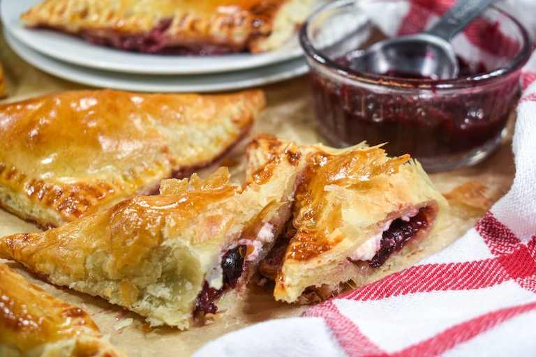 A sliced puff pastry triangle filled with cherries and cheese