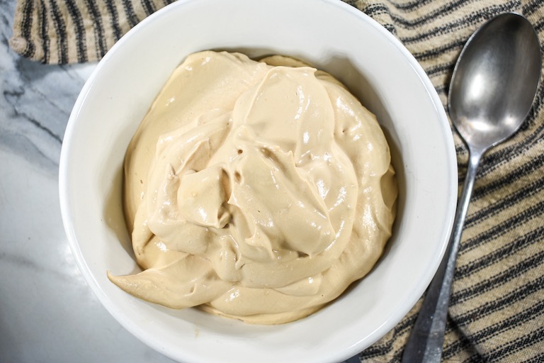 A bowl of coffee whipped cream and a striped towel