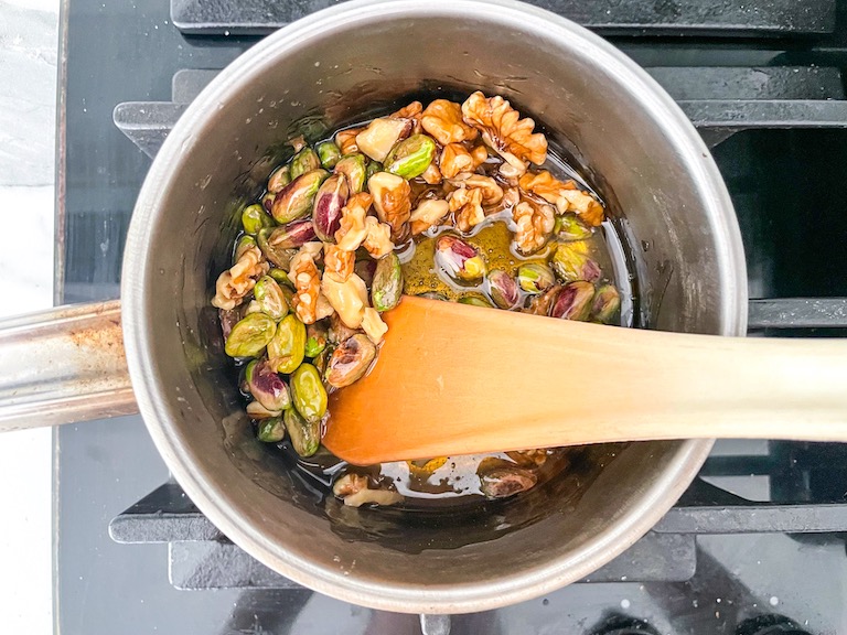 Nuts and honey in a pan with a spoon