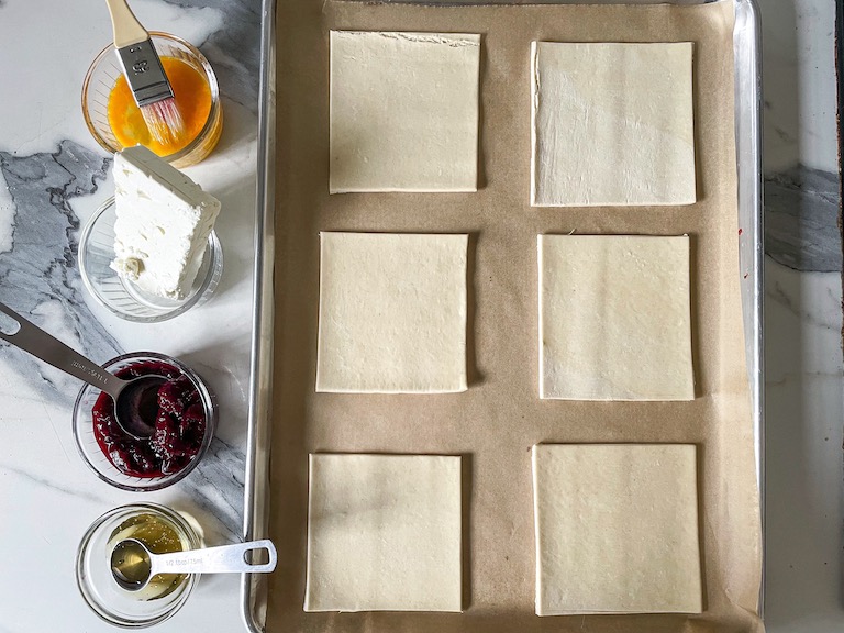 A tray of pastry squares with dishes of ingredients