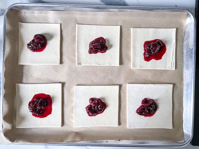 Cherry compote spooned on squares of puff pastry