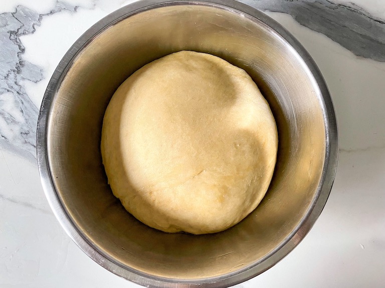 A risen ball of bread dough in a bowl