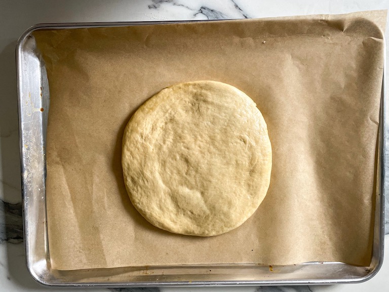 A disc of focaccia dough on a tray