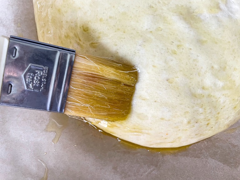 Brushing olive oil on focaccia dough