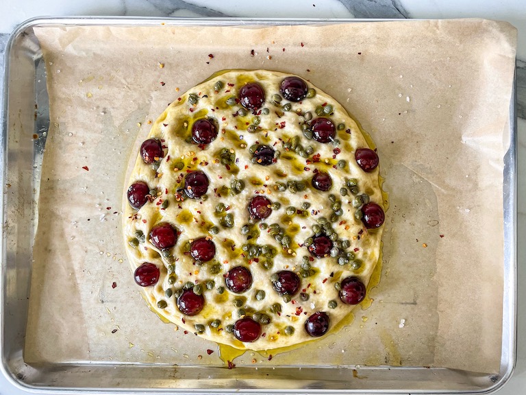 Grape focaccia on a sheet of parchment