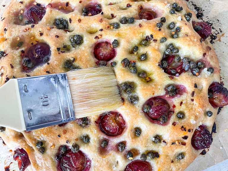 Brushing oil on grape focaccia