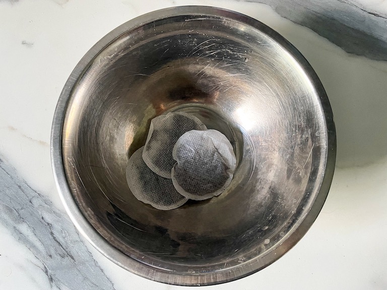 Black tea bags in a metal bowl