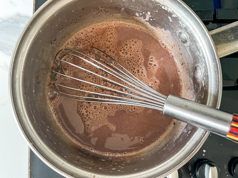 Whisking chocolate into milk in a pan