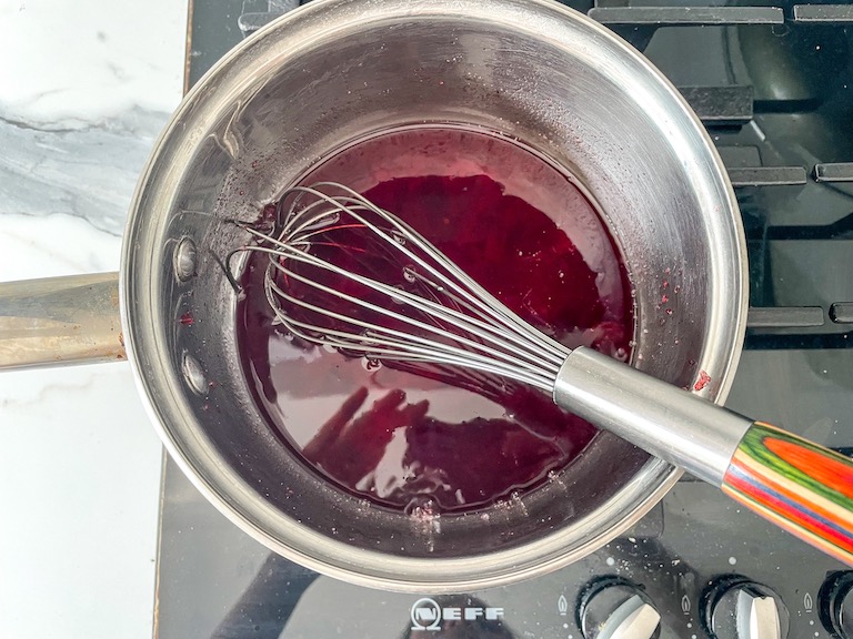 Cranberry juice in pan with whisk