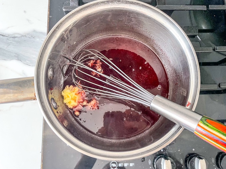 Cranberry juice and ginger in pan with whisk