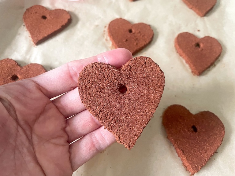 Hand holding an applesauce and cinnamon ornament shaped like a heart