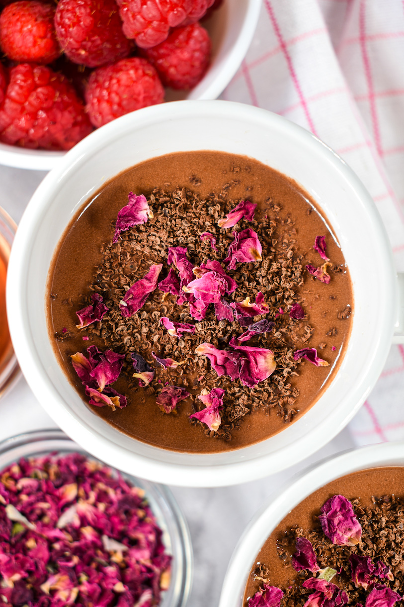 Mug of raspberry rose hot chocolate, dish of rose petals, and bowl of raspberries