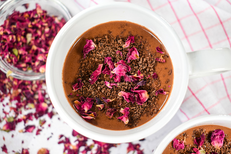 Mug of raspberry and rose hot chocolate garnished with chocolate and dried rose petals