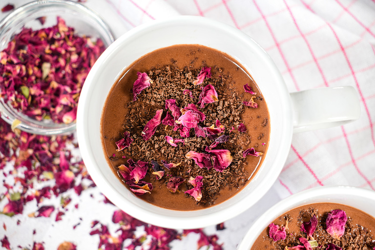 A mug of hot chocolate with chocolate shavings and rose petals on top