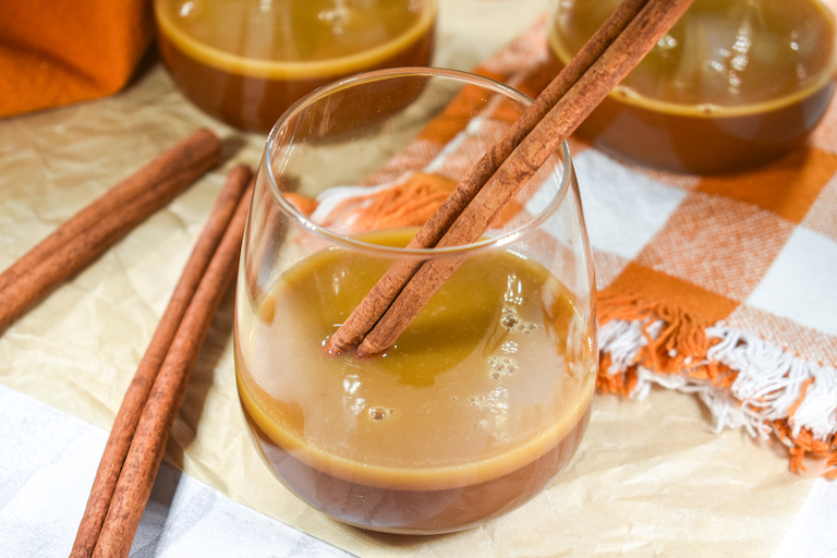 A glass of hot buttered brandy with a cinnamon stick