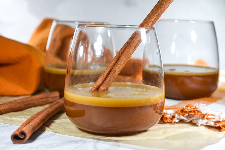 Hot buttered brandy in a glass garnished with a cinnamon stick