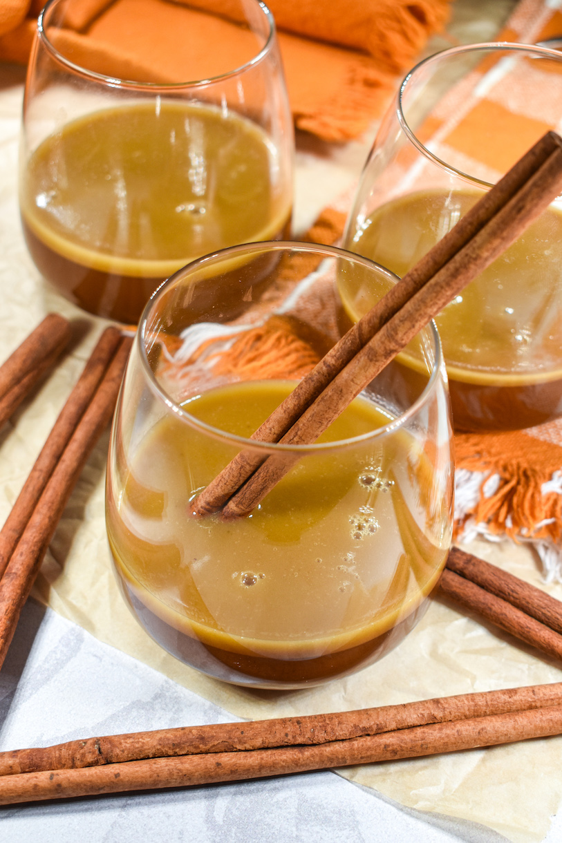 Three glasses of hot buttered brandy arranged on an orange tea towel