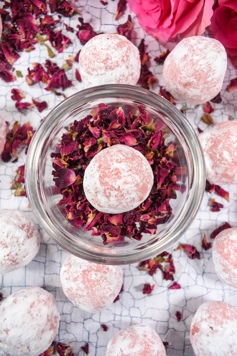 A dish of rose petals with a pink truffle on top
