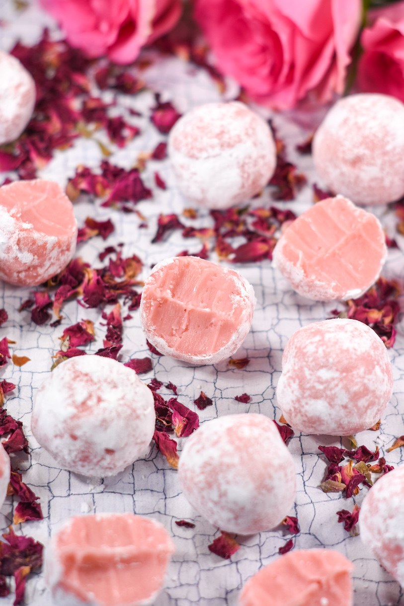 rose truffles and rose petals on a white textured surface