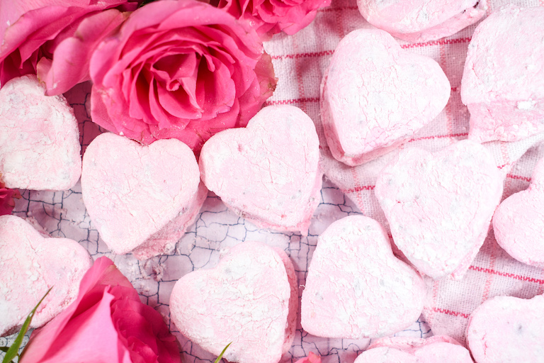 Rosewater marshmallows and fresh roses on a textured surface