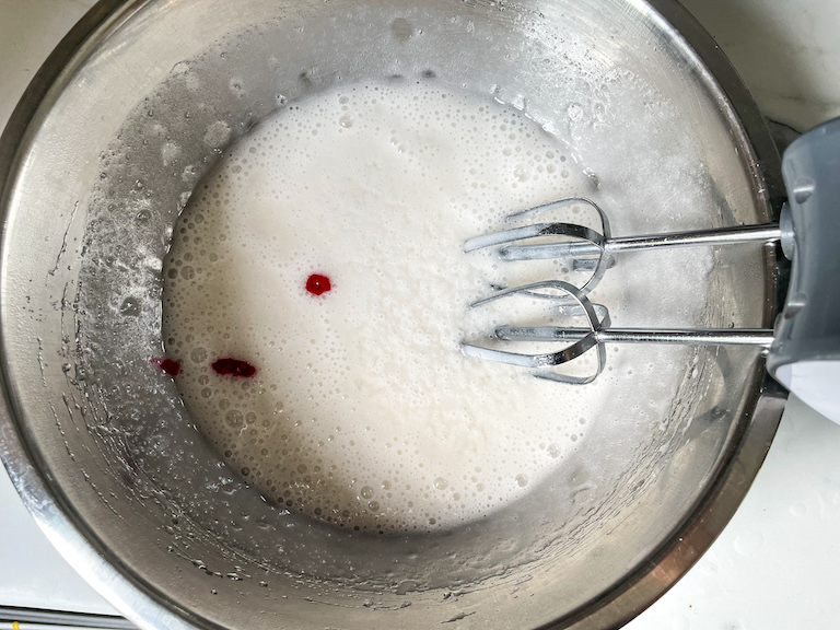 Drops of pink food coloring in white marshmallow