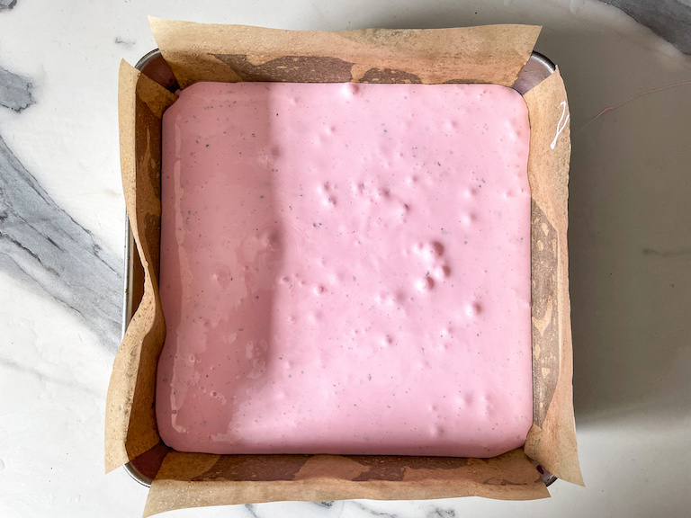 Pink marshmallow mixture poured into a square tin