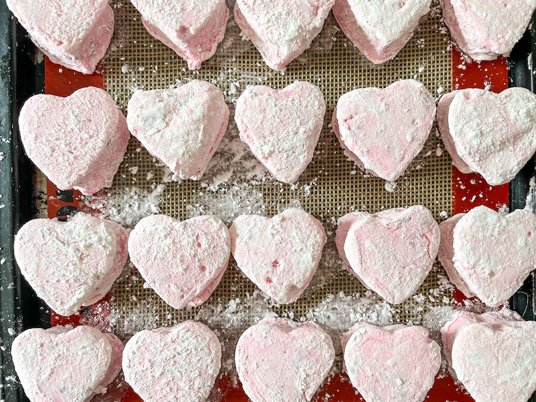 Cornflour-dusted pink heart marshmallows arranged in rows on a tray