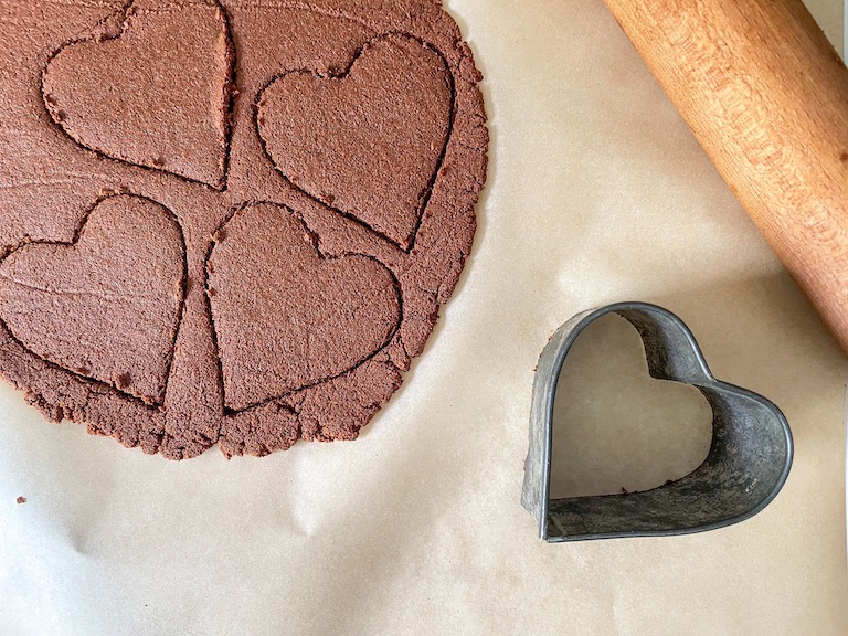 Heart cutter cutting cinnamon dough into shapes