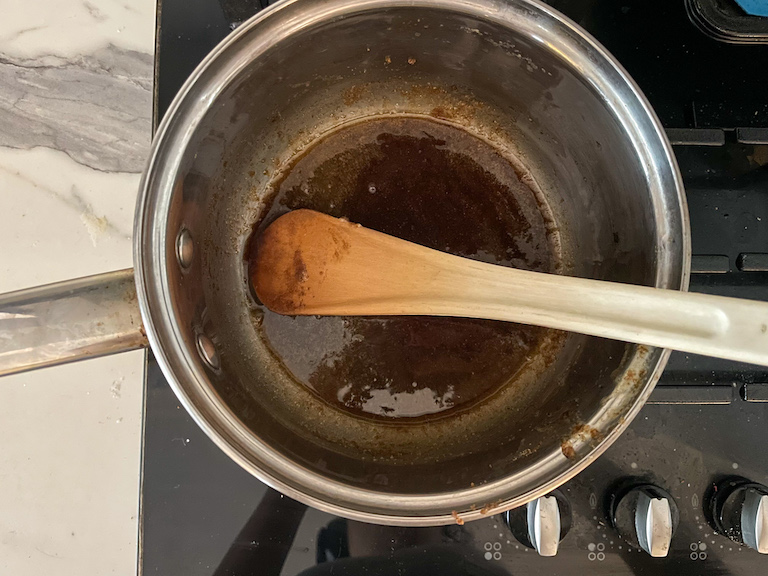 A pan with brown sugar and butter and a spoon