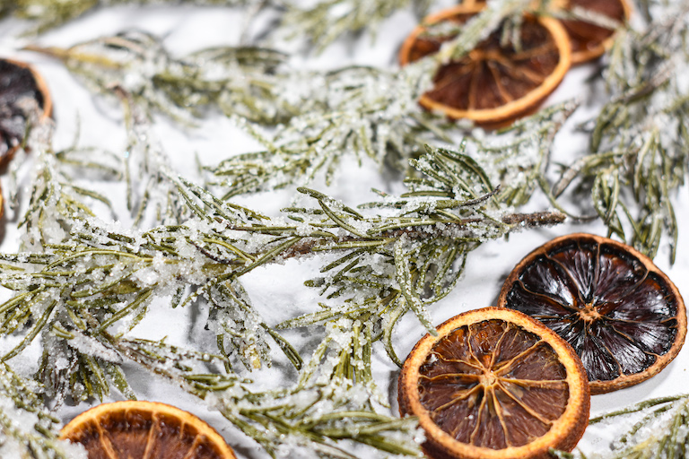 Sugared rosemary and orange slices on a white surface